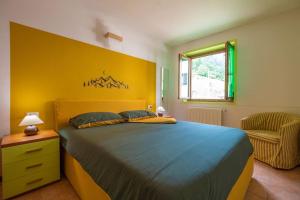 1 dormitorio con cama azul y pared amarilla en Happy Guest Apartments - Alpin Vista Colere en Colere