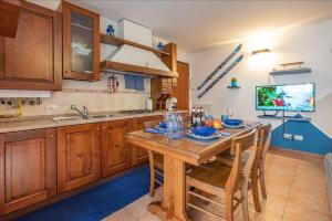 una cucina con tavolo in legno, sedie e TV di Happy Guest Apartments - Alpin Vista Colere a Colere