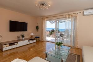 a living room with a tv and a large window at Apartments Nada in Selce