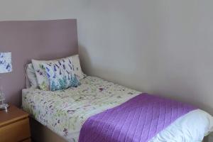 - un petit lit avec une couette violette et un oreiller dans l'établissement Tullyally's View, à Red Castle