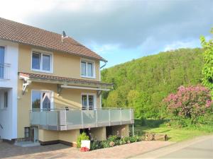 a house with a balcony with a hill in the background at Haus Landlust in Edersee