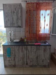 a dirty kitchen with a sink and a window at Mani Stevi Home in Agriliá