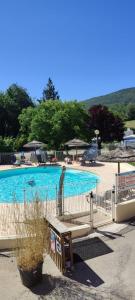 a large blue swimming pool with chairs and umbrellas at Camping aux Vallons in Bauduen