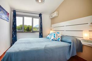 a bedroom with a blue bed with a window at Villa Antonella - Pool and Sea view in Castellammare del Golfo