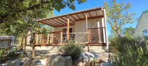 a tiny house with a deck on a hillside at Camping aux Vallons in Bauduen