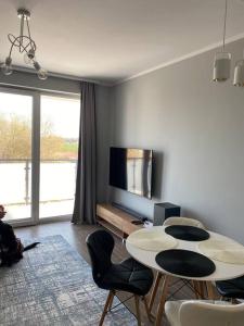 a living room with a table and chairs and a tv at Nowoczesny apartament przy ul Plażowej, Sarbinowo in Sarbinowo