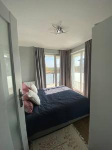 a bedroom with a bed with pillows and a window at Nowoczesny apartament przy ul Plażowej, Sarbinowo in Sarbinowo