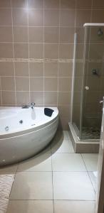 y baño con bañera y ducha acristalada. en Rietvlei Guesthouse Main House, en Margate