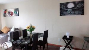 a living room with a dining room table with a vase of flowers at Menlyn Bizcation Accommodation in Pretoria +7 photos