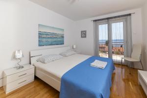 a white bedroom with a bed and a balcony at Apartments Nada in Selce