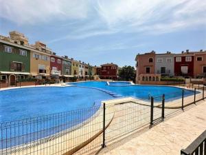 ein großer blauer Pool mit Gebäuden im Hintergrund in der Unterkunft Your Poolside Paradise by the Sea in Port Saplaya