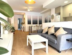 ein Wohnzimmer mit Sofa und Tisch in der Unterkunft Your Poolside Paradise by the Sea in Port Saplaya