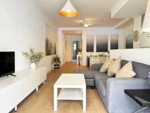 ein Wohnzimmer mit Sofa und Tisch in der Unterkunft Your Poolside Paradise by the Sea in Port Saplaya