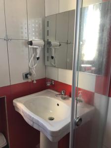 uma casa de banho com um lavatório branco e um espelho. em HOTEL SARDA em Vau i Dejës