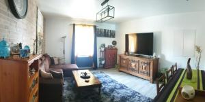 een woonkamer met een bank en een tv bij Chambre cosy entre mer et montagne in Ascain