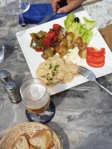 a plate of food with a salad and a glass of beer at Hotel Des Bains in Veulettes-sur-Mer