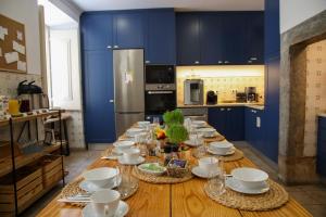里斯本的住宿－LR Guest House，厨房配有蓝色橱柜和长木桌及餐具