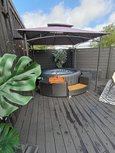 una bañera de hidromasaje bajo una sombrilla en una terraza en The POD Unique & Stylish Luxury Accommodation With Hot Tub, en Swanlinbar
