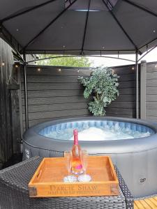 a hot tub with a bottle and two glasses on a table at The POD Unique & Stylish Luxury Accommodation With Hot Tub in Swanlinbar