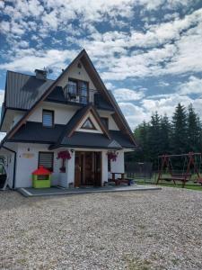 une maison avec un toit en gambrel et une aire de jeux dans l'établissement Pokoje Gościnne Kurosik, à Zakopane
