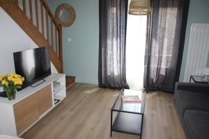 a living room with a couch and a tv at Maisonnette Au 15 in Auxerre