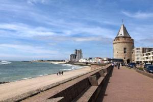 a beach with a clock tower next to the ocean at Next To Sea in Vlissingen