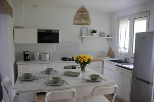 a white kitchen with a table with flowers on it at Maisonnette Au 15 in Auxerre +2 photos