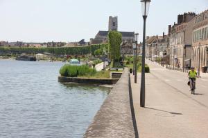 a person riding a bike on a bridge over a river at Maisonnette Au 15 in Auxerre