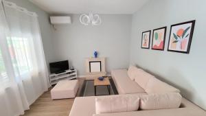 salon z białą kanapą i telewizorem w obiekcie Cozy villa, Golem beach. w mieście Golem