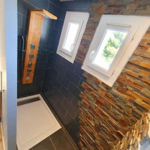 a bathroom with two windows and a stone wall at Joli haut de villa 3 chambres climatisé avec jacuzzi in Marignane