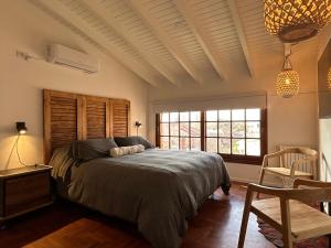 um quarto com uma cama, uma cadeira e uma janela em Oeste suites em Mendoza