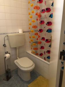 a bathroom with a toilet and a shower curtain with fish at Casa da Avó Bi in Vila Nova da Barquinha +20 photos
