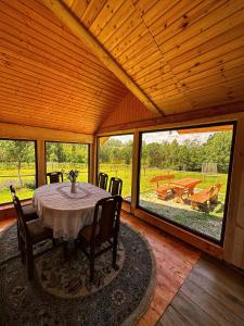 uma sala de jantar com mesa, cadeiras e janelas em Căsuța din Stejari-Transalpina em Novaci-Străini