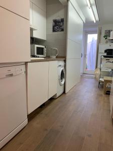 uma cozinha com armários brancos e uma máquina de lavar e secar roupa em Encanto Casa com Spa Jacuzzi Open Space em Tinalhas