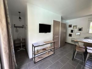 sala de estar con TV y mesa en Séjour Romantique Jacuzzi intérieur Privé, en Le Vigan