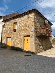 ein Steingebäude mit gelben Türen und einem Balkon in der Unterkunft Encanto Casa com Spa Jacuzzi Open Space in Tinalhas