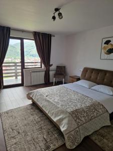 a bedroom with a large bed and a balcony at Agropensiunea La Uța in Rebrişoara