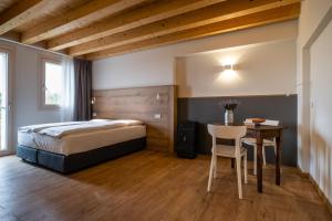 Agriturismo al Comarel في Tarzo: غرفة نوم بسرير وطاولة مع كرسي