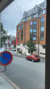 ein rotes Auto, das auf einer Straße vor einem Gebäude geparkt ist in der Unterkunft Eiganesveien 1/sentralt,2 sov. in Stavanger