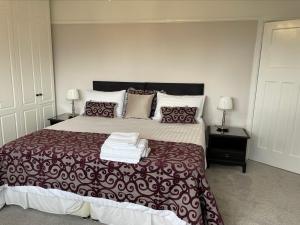 een slaapkamer met een groot bed en 2 nachtkastjes bij Walton House in Frinton-on-Sea