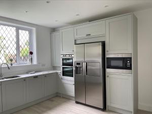 cocina con armarios blancos y nevera de acero inoxidable en Walton House en Frinton-on-Sea