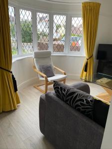 a living room with a couch and a chair and windows at Walton House in Frinton-on-Sea