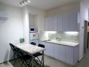 a kitchen with white cabinets and a table with chairs at On the sea in Ashkelon