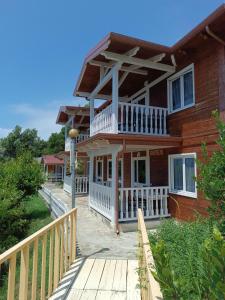 Cette grande maison en bois dispose d'une véranda et d'une terrasse. dans l'établissement Plazhi Gjeneralit - Small Cabins - Bungalows - Apartaments - Villas - Suite, à Kavajë