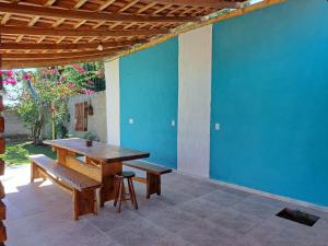 une table en bois et des bancs sur une terrasse avec un mur bleu dans l'établissement Casa de Campo Pedra Bicuda, à Brazópolis