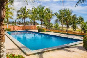 una piscina con palmeras en el fondo en Pousada Sitio Phoenix, en Prea