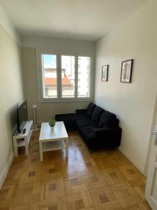 uma sala de estar com um sofá preto e uma mesa em T4 3 Chambres proche grattes ciel, Villeurbanne, meublé em Villeurbanne