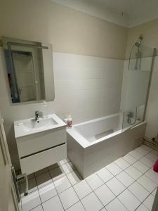 y baño con bañera, lavabo y espejo. en T4 3 Chambres proche grattes ciel, Villeurbanne, meublé en Villeurbanne