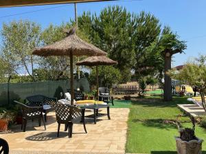 un patio con mesas, sillas y una sombrilla en Quinta dos Viegas, en Faro