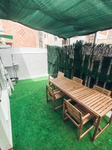 a wooden table and chairs on a patio with green grass at Apartamento 15' Barcelona centro in Santa Coloma de Gramanet